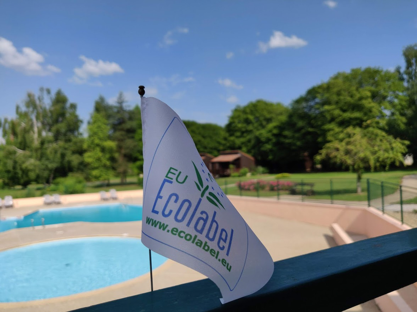 Piscine du hameau avec le drapeau écolabel au premier plan.